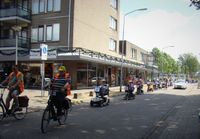 De bonte stoet van scootmobielen gaat langs het winkelcentrum Rauwenhof in Tiel en trekt daar veel bekijks.